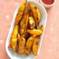 Lemon Roasted Potatoes served on a white oblong dish with some tomato ketchup
