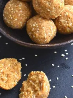 Close up off half ladoo seen with few ladoos in the background on a black bowl