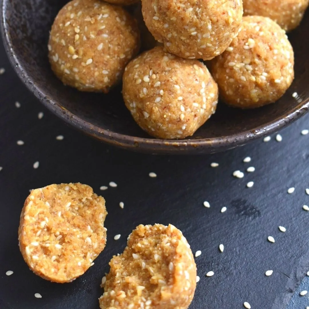 Close up off half ladoo seen with few ladoos in the background on a black bowl