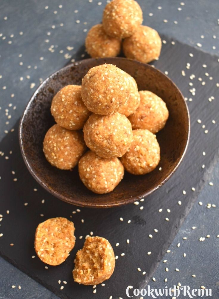 Close up off half Til Khoya ladoo seen with few ladoos in the background on a black bowl and on a black board