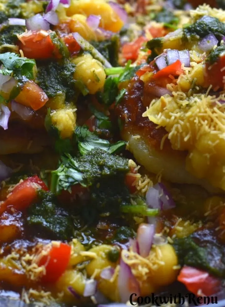 Close up look of Ragda Pattice with a generous garnish of chutney, tomato, onion and sev