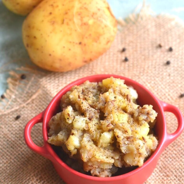 Farali Kali Mirch Aloo served in a red bowl. seen aside are some potatoes.