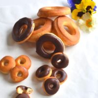 Sugar and Chocolate glazed mini and big size donuts with some edible flowers on the side