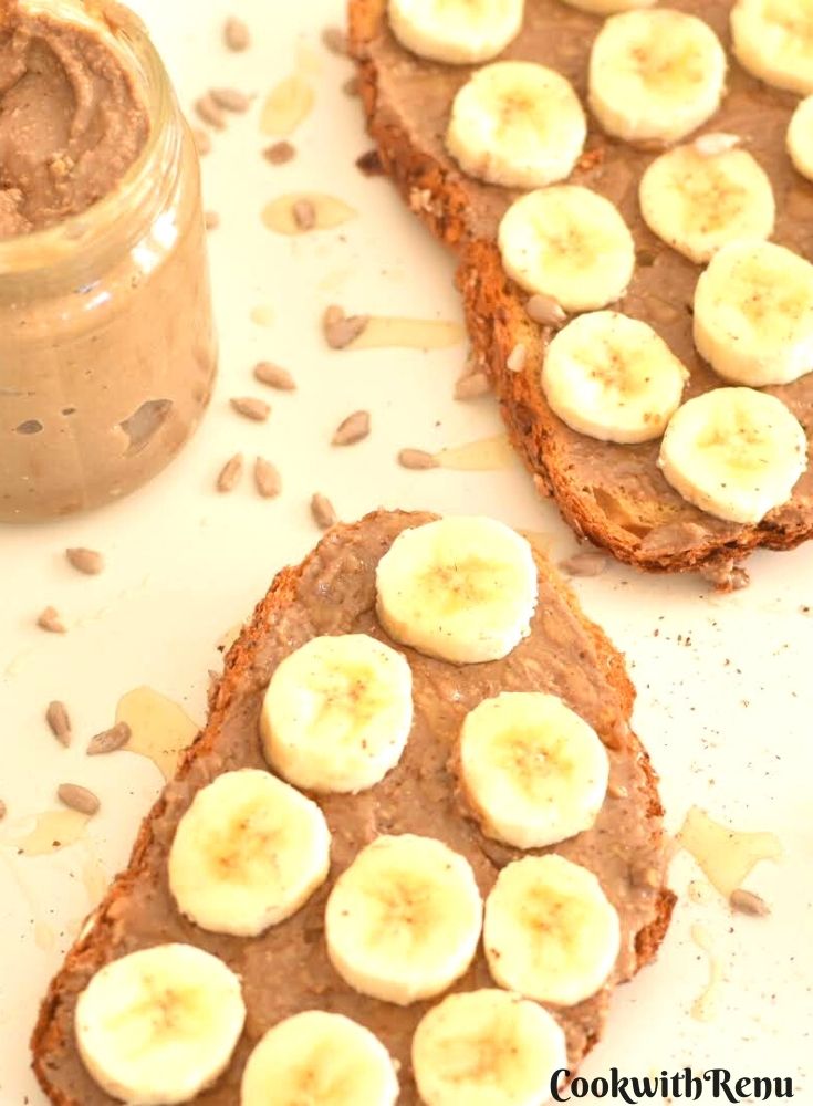 Seed Butter in glass jar along with 2 slices of toast spread with sunflower seed butter along with banana slices and a drizzle of honey and cinnamon