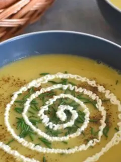 Leek & Potato Soup served in a bowl with a generous garnish of chives and sour cream.