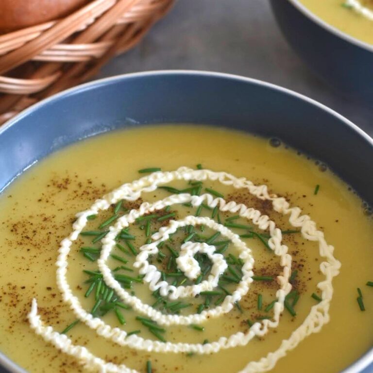 Leek & Potato Soup served in a bowl with a generous garnish of chives and sour cream.