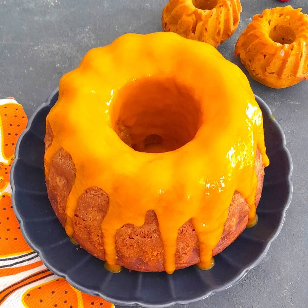 Easy Eggless Mango Bundt cake with a generous drizzle of mango pulp and seen in the background are 2 more small Bundt muffins