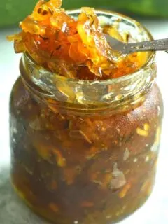 Lemon Ginger Zucchini Marmalade presented in a glass jar, with a close up look of jelly in a spoon