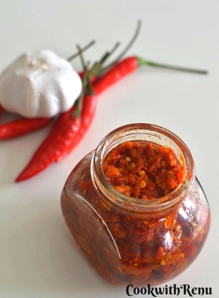 Harrisa Paste in a glass jar. Seen in the background are some red chilly and onion