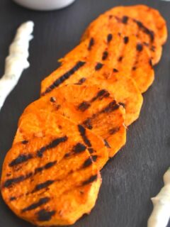 Peri-Peri Grilled Sweet Potato served on a black cheese board along with some yogurt dip