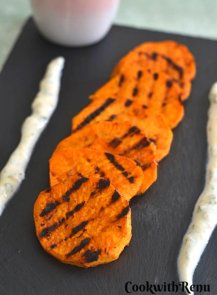 Peri-Peri Grilled Sweet Potato served on a black cheese board along with some yogurt dip