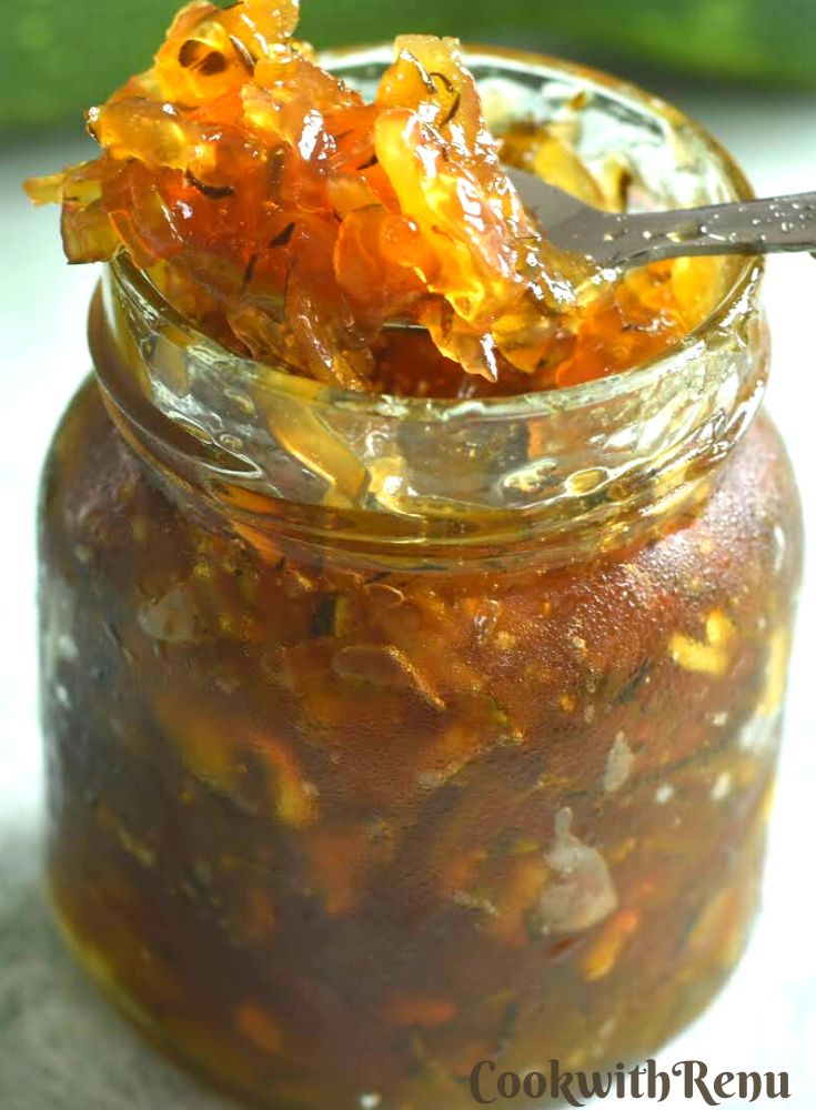 Courgette Jam presented in a glass jar, with a close up look of jelly in a spoon