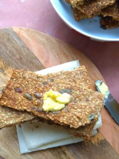 Knäckebröd – Swedish Multi-Seed Crispbread served on a brown board with some butter spread on top