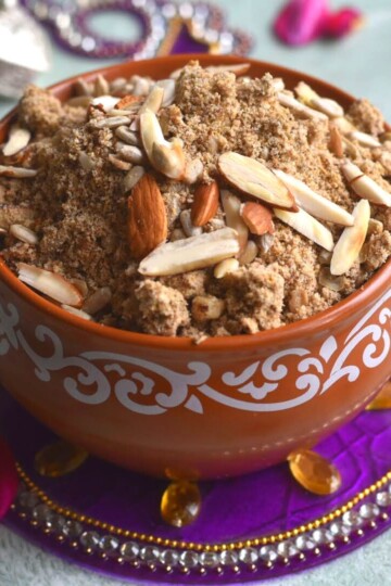 Kuttu aur Dhaniya Panjiri served in a brown bowl. Seen along side are some rose petals and some festive decorations