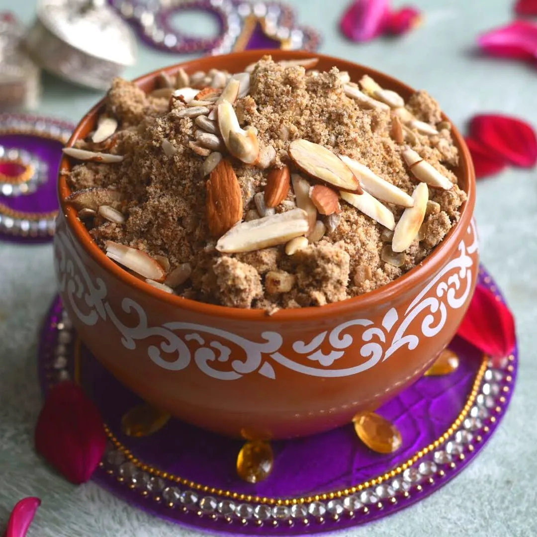 Kuttu aur Dhaniya Panjiri served in a brown bowl. Seen along side are some rose petals and some festive decorations