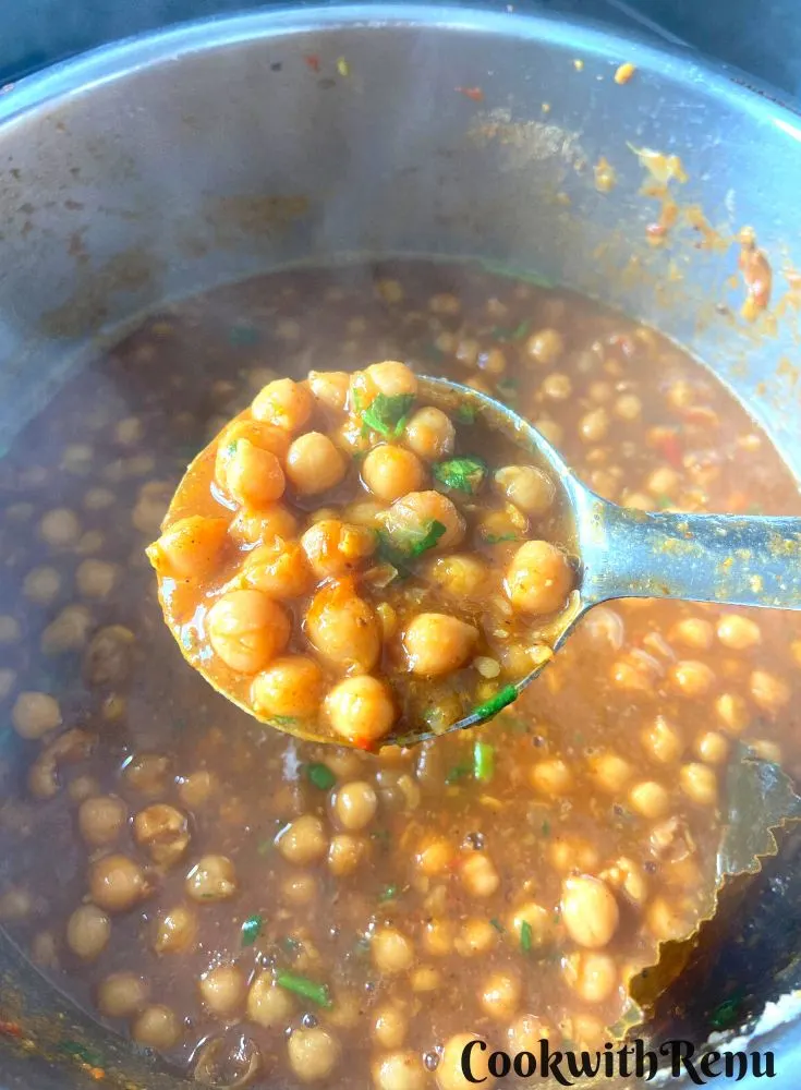 close up looked of Cooked chana masala seen in a laddle over an Instant Pot.