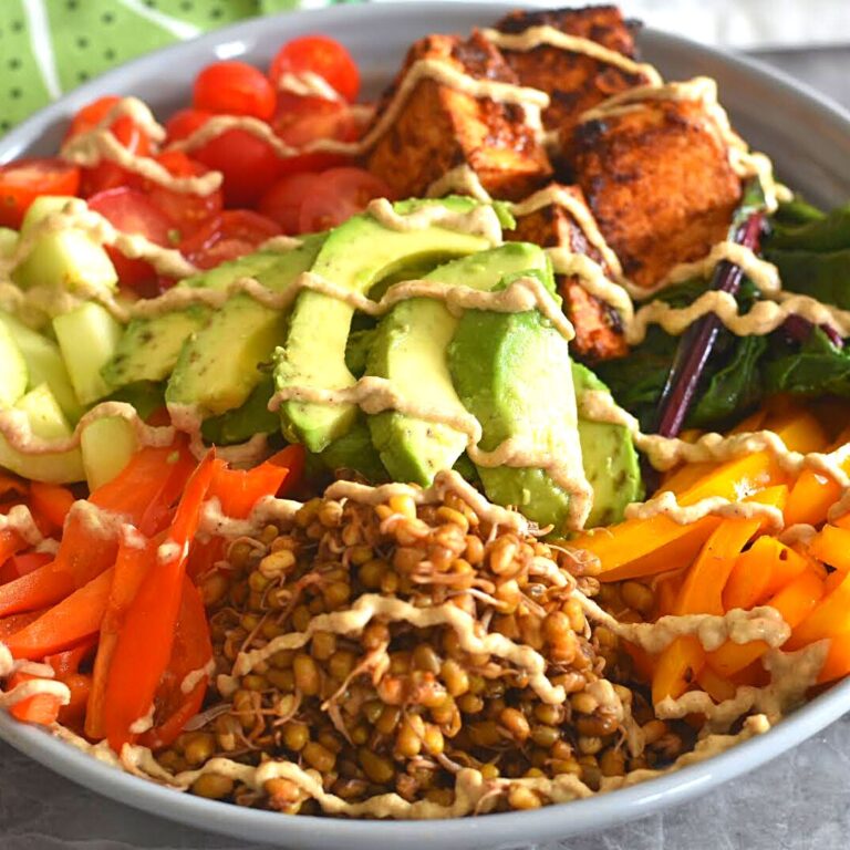 Cooked Moong Sprouts, Tofu, Vegetables and fruits arranged in a grey bowl with tahini lemon dressing.