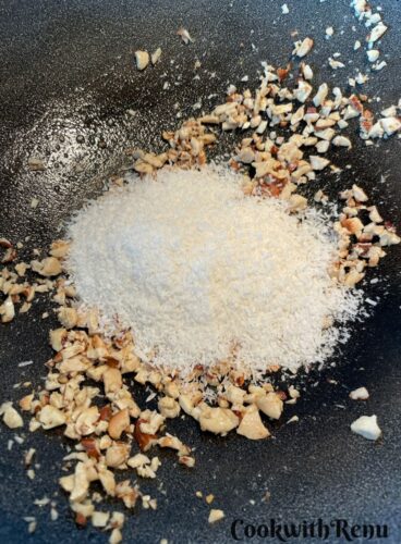 Adding of desiccated coconut in nuts for roasting in an iron wok.