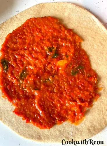 Adding pizza sauce in the rolled bread.