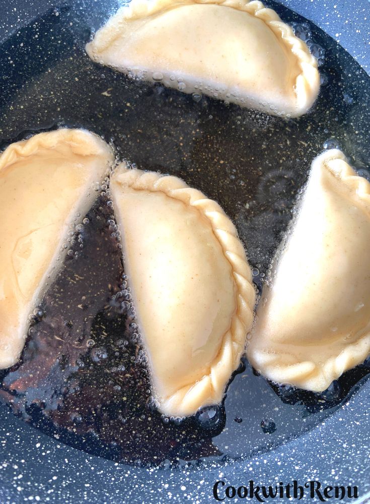 Gujiya getting fried in oil.