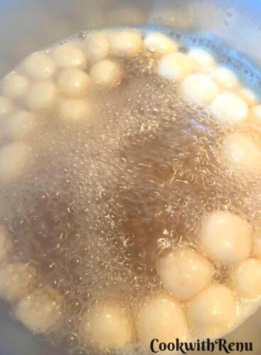 Rasgulla getting cooked in sugary boiling water.