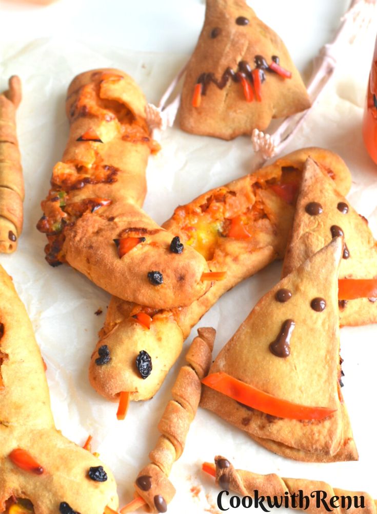 Spooky Halloween Stuffed breads arranged on a white parchment paper paper, with some festive decorations seen on the side.