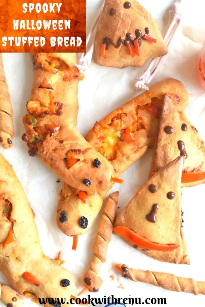Spooky Halloween Stuffed bread arranged on a white parchment paper paper, with some festive decorations seen on the side.