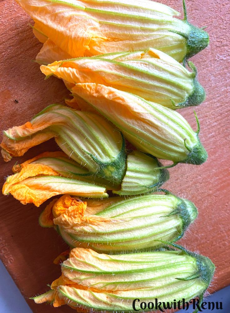 Squash Blossoms arranged in a line on a chopping board.