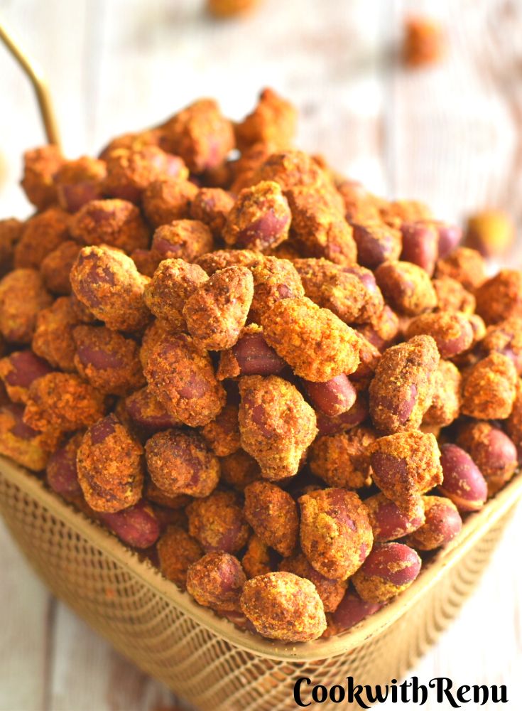 Air Fryer Masala Peanuts in a golden brown colander, with some peanuts scattered around.