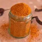 Gun powder in a glass jar with some chilies and some powder lying around