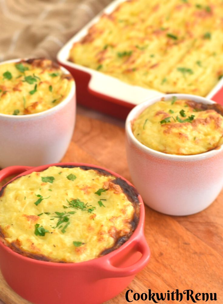 Air Fryer Shepherdless Pie in individual ramekin molds in front on a brown cheese board and seen behind in a rectangular dish.