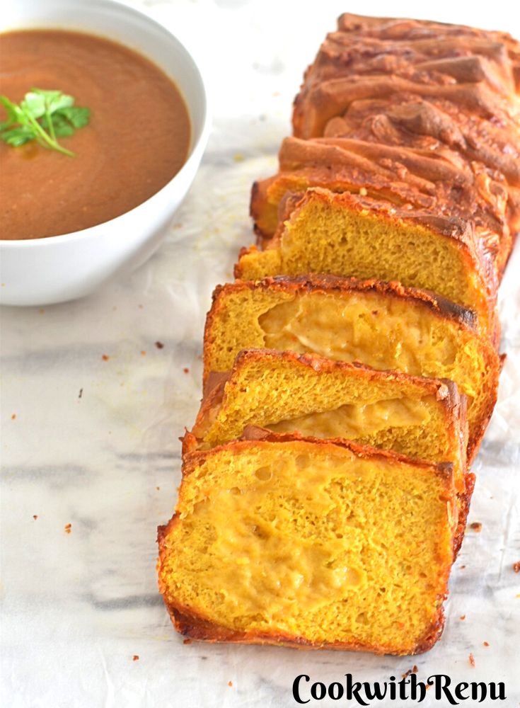 Sliced Pumpkin Cheese Bread served on a white board with some soup on the side.