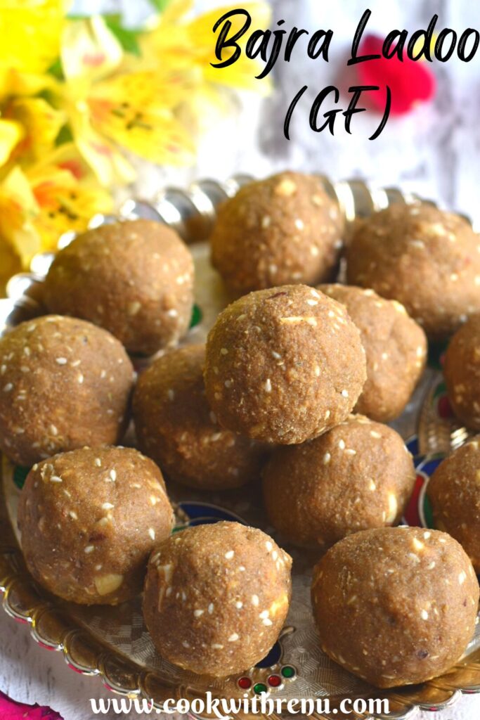 Gluten-free Pearl millet energy bites or truffles served in a golden tray with some flowers on the side.