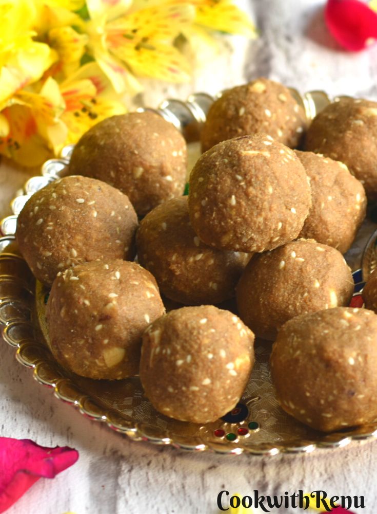 Top view of Gluten-free Bajra ladoo served in a golden tray with some flowers on the side.