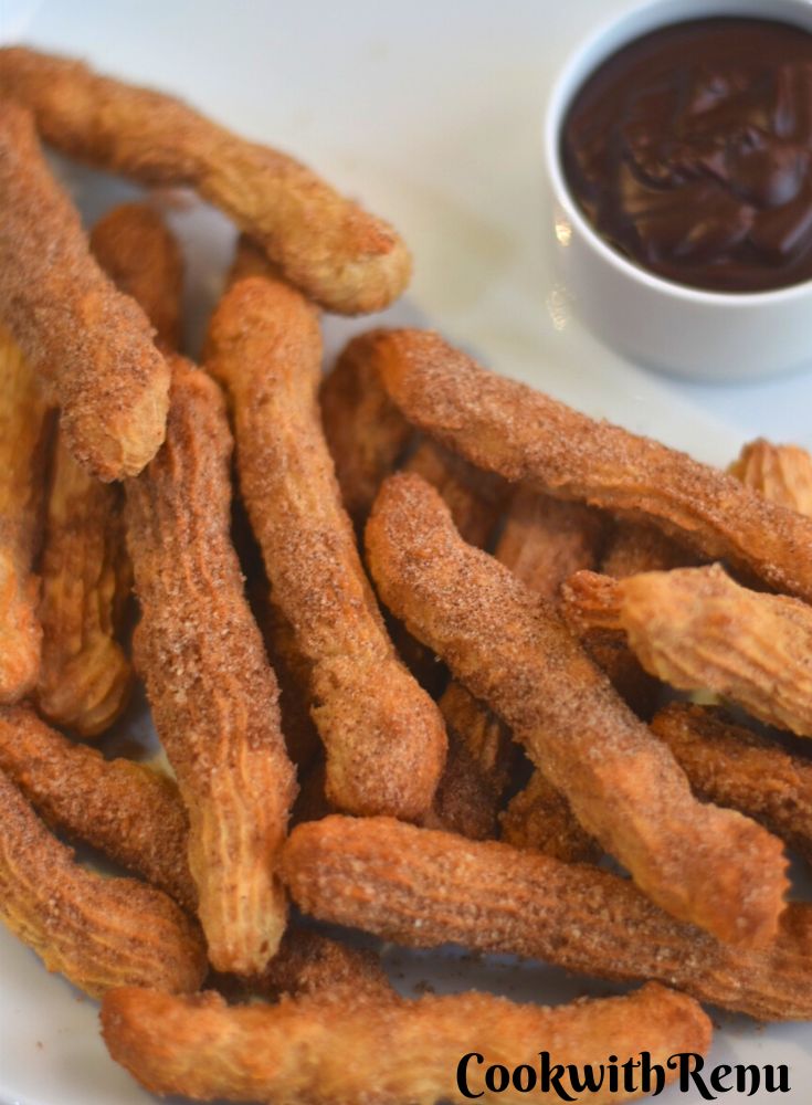 Vegan Air Fryer Churros served on a white plate served with some dipping chocolate sauce.