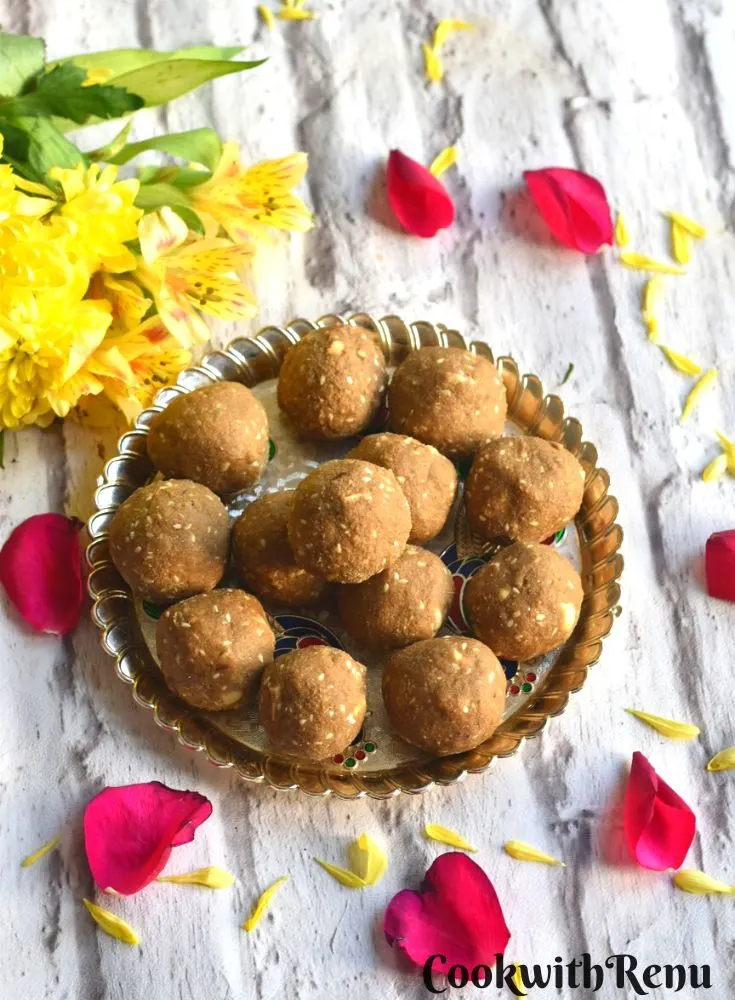 Gluten-free Pearl millet energy bites or truffles served in a golden tray with some flowers on the side.