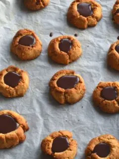 Chocolate Filled Hazelnut Thumbprint Cookies on a baking tray lined with parchment paper.