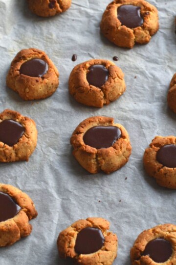 Chocolate Filled Hazelnut Thumbprint Cookies on a baking tray lined with parchment paper.