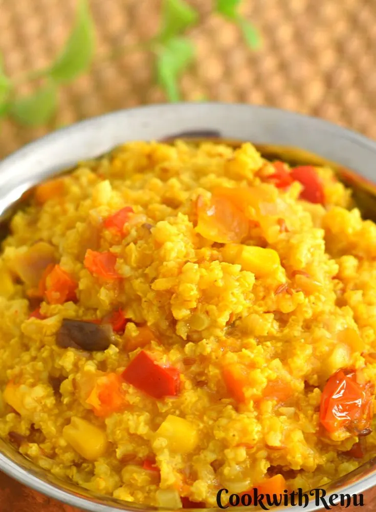 Millet Upma served in a bowl and on a brown mat with some mint on the side.