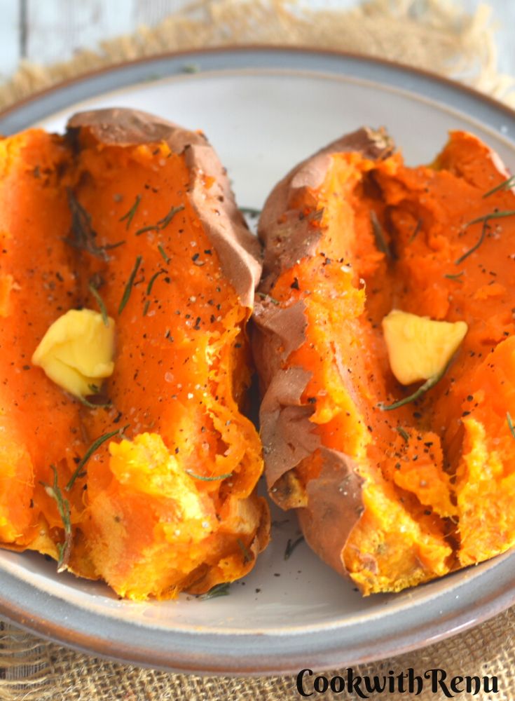 2 Air Fryer Baked Sweet Potato served with a dollop of butter and rosemary, black pepper powder and salt sprinkled on it. They are served on a white plate with grey border.