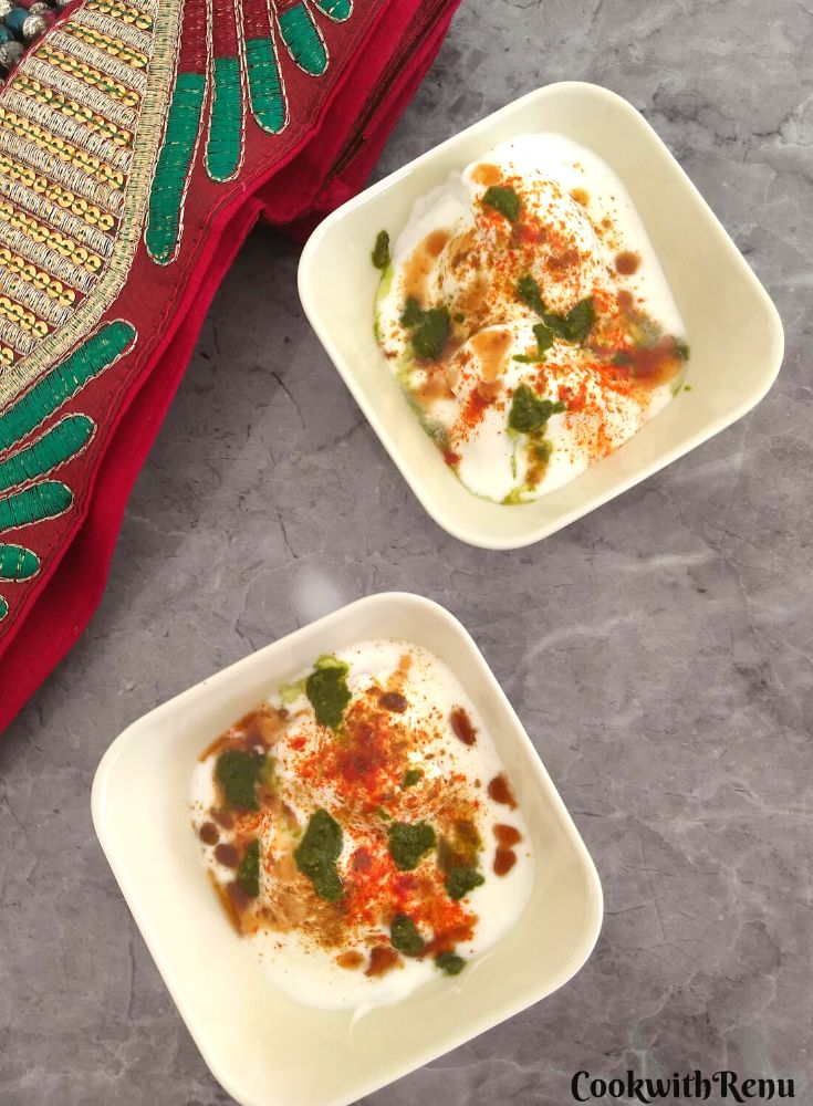 Holi special Dahi Bhalla served in 2 white bowls, topped with chutneys.