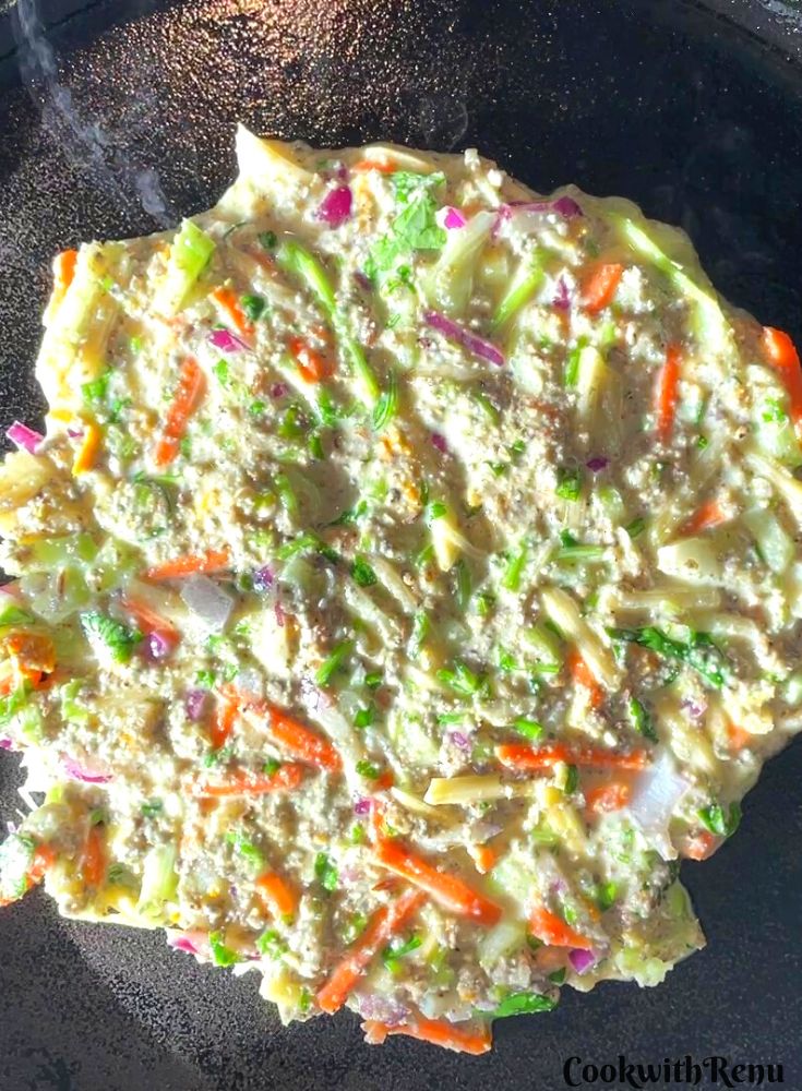 Kambu chilla spread on a cast iron pan ready to be cooked.