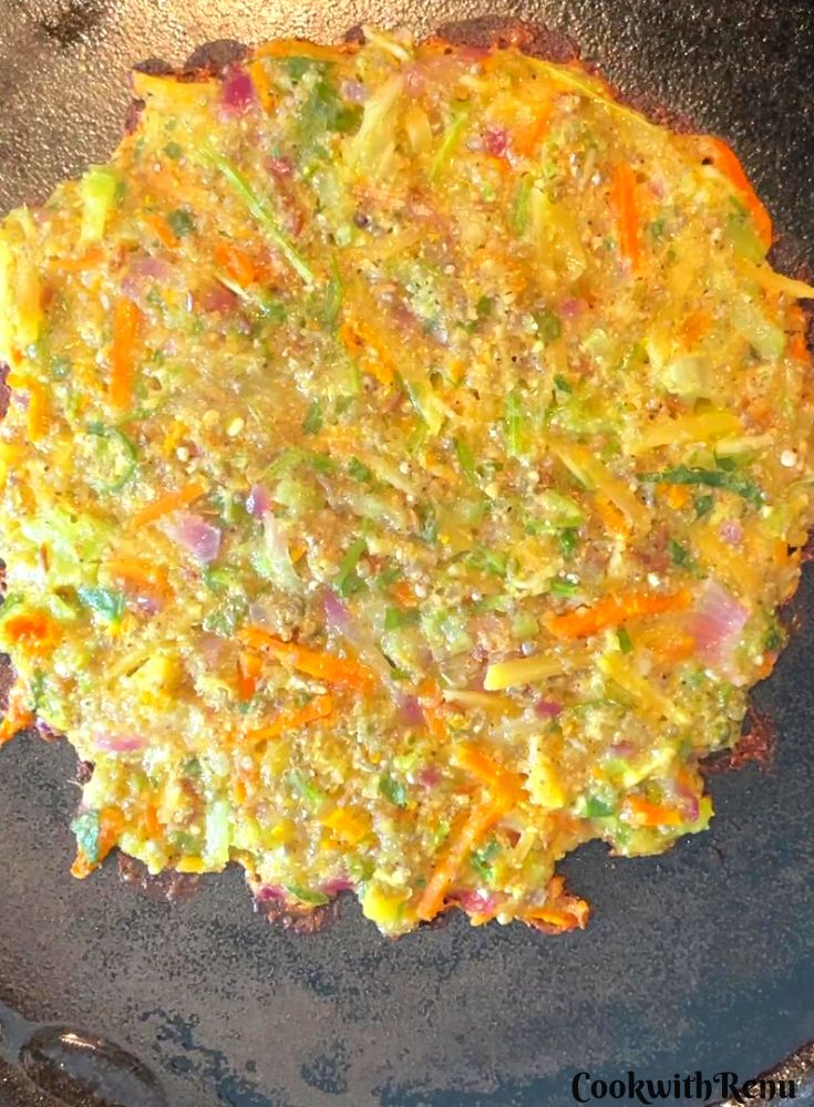 Pearl millet chilla getting cooked on underside on a cast iron pan.