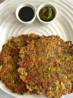 Sprouted Bajra Vegetable Chilla served in a white plate along with tamarind and coriander chutney.