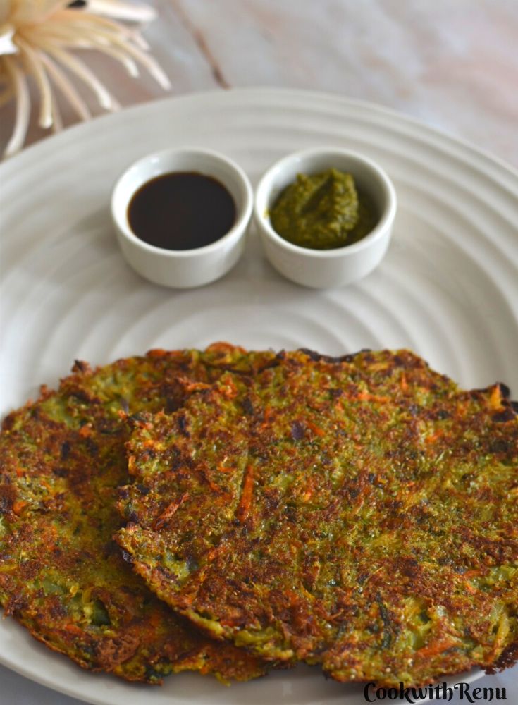 Sprouted Bajra Vegetable Chilla or Pearl millet savory pancake served in a white plate along with tamarind and coriander chutney.