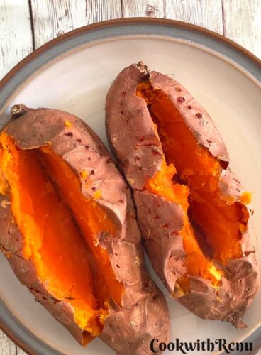 Whole Baked Air Fryer Sweet Potato open in the center and served on a white plate with grey border.