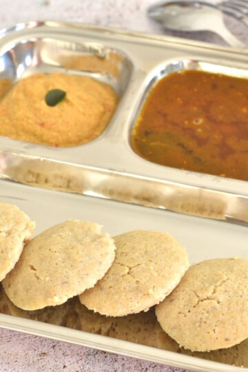 4 Quinoa Idli served in a steel divider plate along with chutney and rasam.