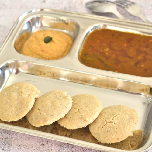 4 Quinoa Idli served in a steel divider plate along with chutney and rasam.