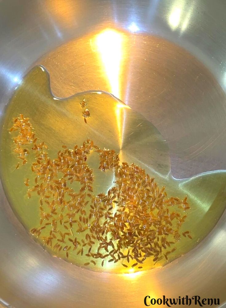 Cumin added to oil in a pan.