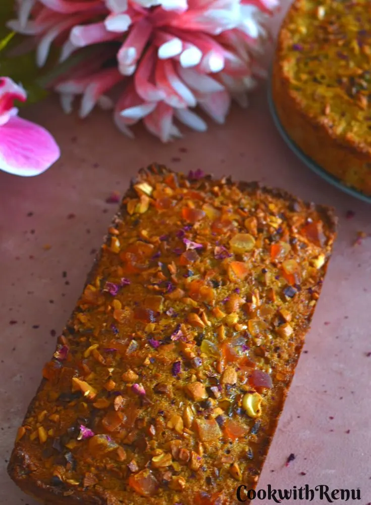 Loaf Goan Baath or Batica Cake is seen on a pink board with a round cake and flowers in the background.